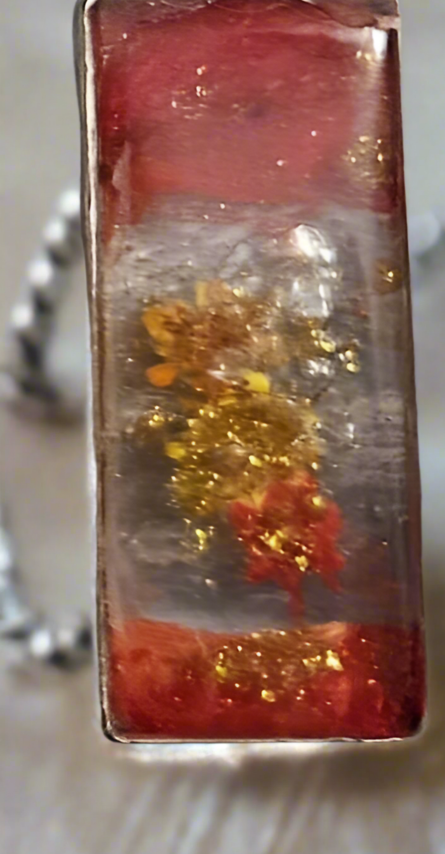 Close-up of autumn botanical rectangle resin pendant showing pressed flowers and gold flakes
